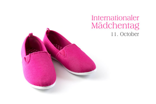 pink kid shoes isolated on a white background, german text  Internationaler Maedchentag 11 October, that means international day of the girl child, copy space
