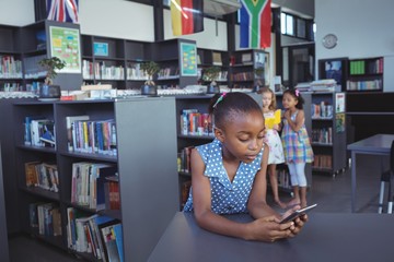 Girl using cellphone at desk in library