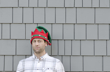 Man in a Christmas hat looking to the side with a smirk.