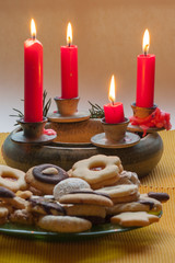 Adventskranz mit roten Kerzen und einem Teller Weihnachtsplätzchen