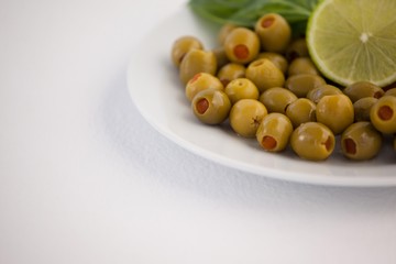 Cropped image of olives in plate with lemon