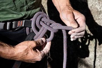 Tableaux ronds sur plexiglas Alpinisme mountain climber tying rope in double bowline knot