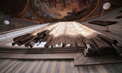 Veduta dal basso di una lunga e antiquata tenda illuminata dai raggi solari all'interno di una chiesa