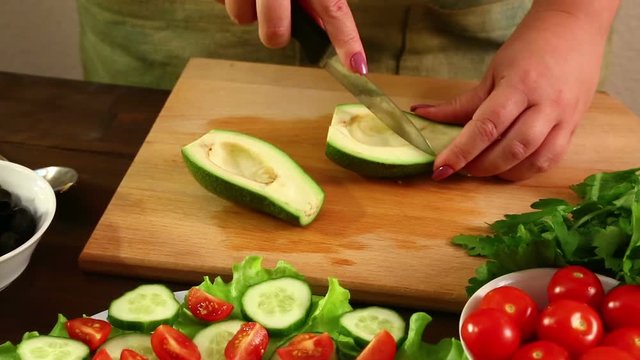 The woman cuts the avocado into small pieces with the knife. Close-up. Shot with a cart with the right to left