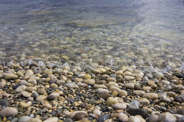 Closeup pebble stones on a beach with soft focus by the sea, waves and skyline