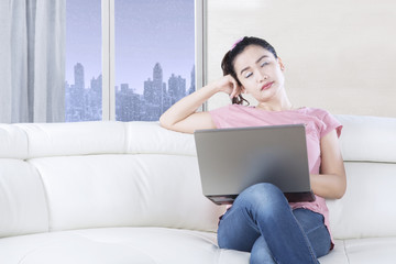 Woman with laptop resting on couch
