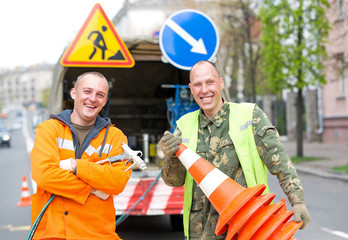 Smiling traffic sign marking technician workers on city street during road surface painting works