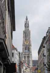 Onze Lieve Vrouwekathedraal (Cathedral of Our Lady) in Antwerp Belgium at the end of the street. Shops line the high street with the cathedral of Antwerp at the end of the street. Tall gothic tower.