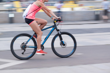 Fototapeta na wymiar the girl rides a bicycle through the summer city