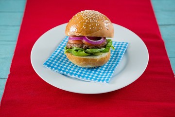 Close up of hamburger served on napkin in plate