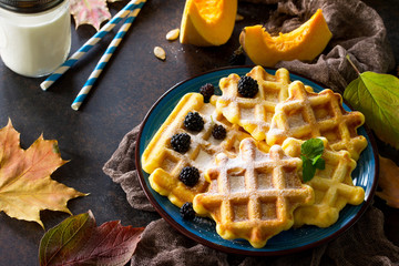 Breakfast table with pumpkin waffles and fresh blackberries on a stone or slate background.