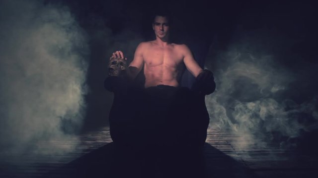 Sexy man sitting in a chair with a skull in the smoke