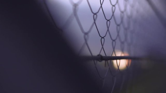 Wire fence. Closeup and rack focus of steel net. Security protection barrier at the racing track in the dusk. Industrial security element. Fence made from steel wire. Metallic security net.