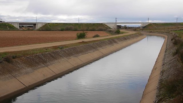Tren de Pasajeros cruzando de izquierda a derecha sobre un canal de agua para el riego agrícola
