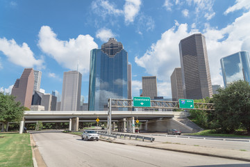 Downtown Houston from Allen Parkway near Sabine street under cloud blue sky. Highway/expressway in front of skyscrapers from central business district. Transportation, architecture and travel concept