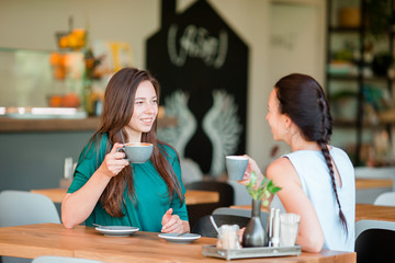 Happy smiling young women with coffee cups at cafe. Communication and friendship concept