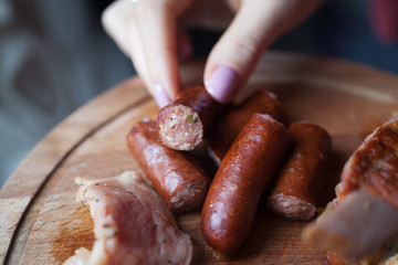 girl hand takes a sausage from the dish with meats