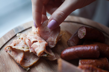 girl hand takes a sausage from the dish with meats