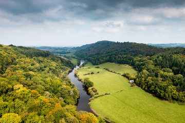 Fototapeta premium A river winding through farmland and trees showing fall coloring