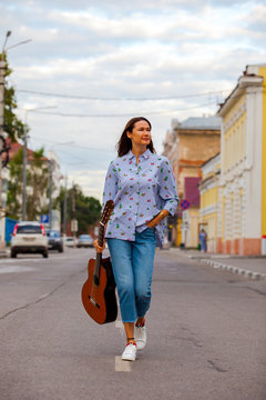 beautiful woman with a guitar walking down the street
