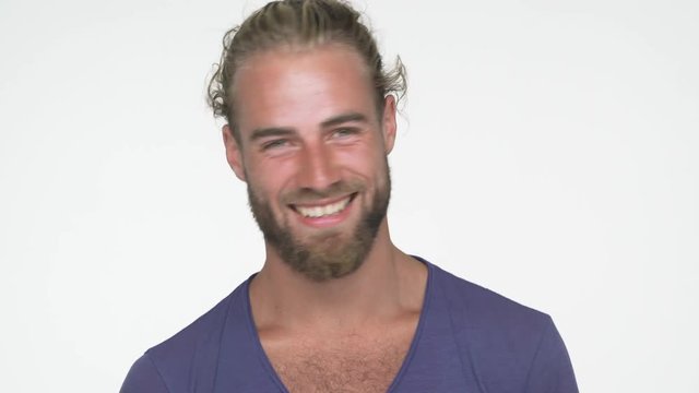 closeup portrait of american handsome guy wearing blue t-shirt looking at camera smiling broadly laughing out loud with white teeth over white background. Concept of emotions