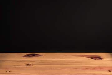 Wooden table or desk with black wall background in vintage tone.