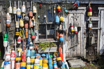 Obraz premium fishing wooden house with nets and buoys. colorful lobster buoys and fishnets hanged on wooden wall