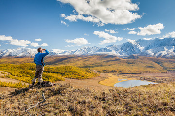 Fototapeta premium A Man looking at the Mountains and a Lake below from Viewpoint.