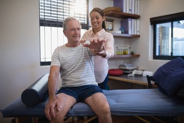 Smiling senior male patient and female doctor looking at hand
