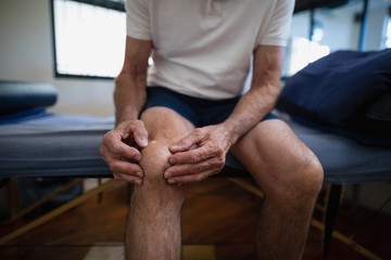 Midsection of senior male patient holding knee in pain