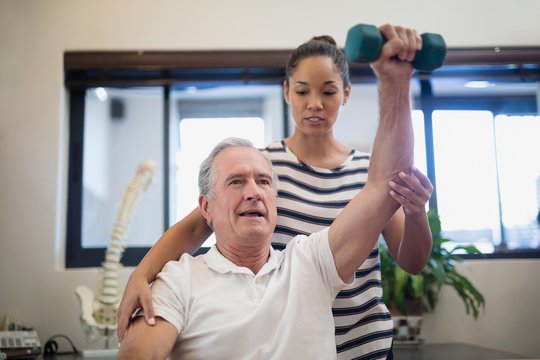 Female doctor looking at senior patient lifting dumbbell © WavebreakMediaMicro