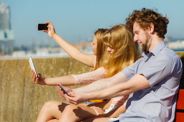 Friends taking selfie photo with smartphone.