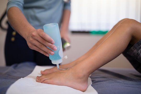 Female therapist pouring scanning gel on feet of boy