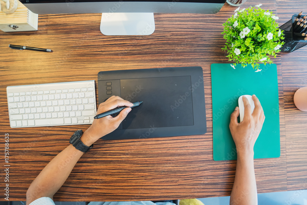 Poster young graphic designer working on modern desktop computer while using graphic tablet at desk in the 