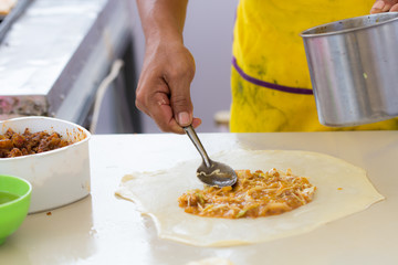 Thai street food of merchant making delicious hot roti for customers
