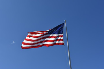 United States of America Flag on a flagpole blown by wind with clear blue sky
