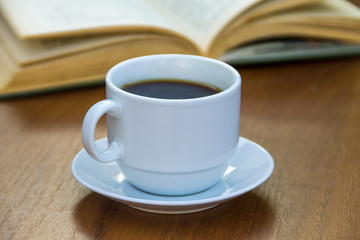 Cup of coffee and book on wooden table