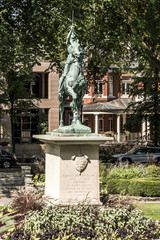 Obraz premium Bronze statue Sancta Joanna D arc - Joan of Arc war memorial in a colorful garden on a sunny day