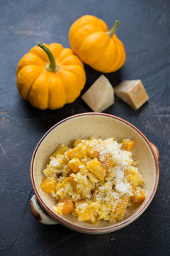 Risotto with pumpkin on a brown stone background, vertical shot, elevated view