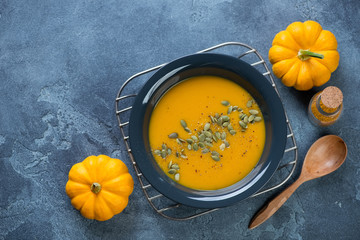 Plate of freshly made pumpkin soup on a metal cooling rack, flat-lay on a blue stone background,...