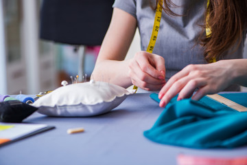 Woman tailor working on a clothing sewing stitching measuring fa