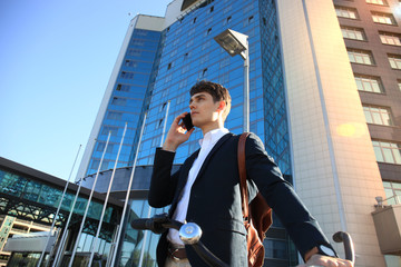 Young businessman with bicycle and smartphone on city street.