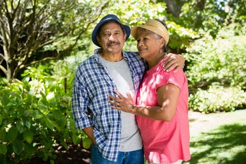 Portrait of senior couple standing with arm around in garden