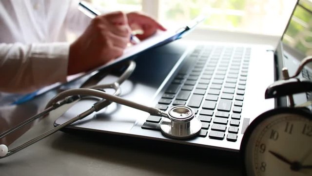 Stethoscope on Medicine doctor's working on laptop computer and hand doctor with stethoscope writing record patient in desk hospital