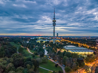 Obraz premium Abendstimmung über dem Olympiapark von München mit dem Olympiaturm im Herbst zum Jahreszeitenwechsel bei Sonnenuntergang
