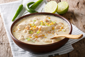 Homemade white chili chicken with beans, lime and corn close-up. horizontal