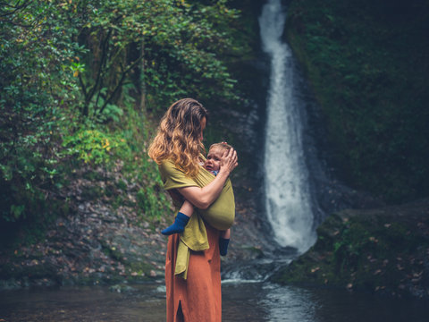 Mother with baby standing by waterfall