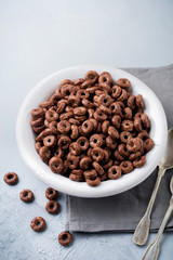Healthy breakfast with chocolate corn rings, red currant berries, yogurt and tea on a gray concrete background. Selective focus. Top view. Copy space.