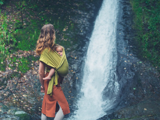 Mother with baby standing by waterfall