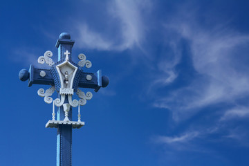 blue, very nicely carved cross with a figurine of Jesus in the blue sky with clouds